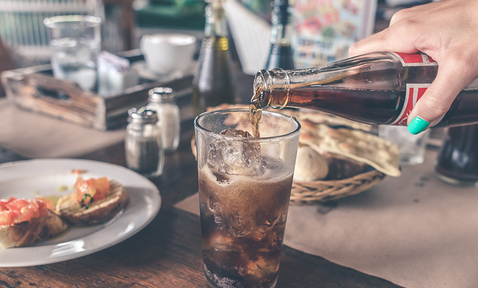 hand holding bottle pouring soft drink
