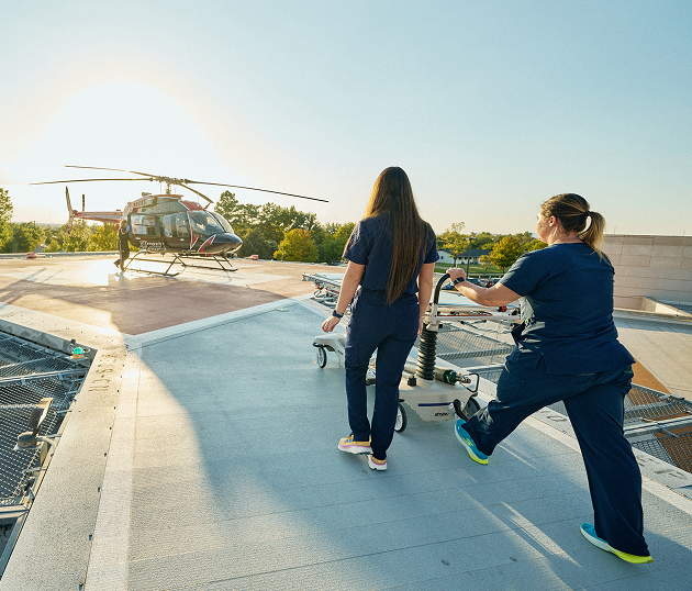Two nurses with gurney heading towards helicopter on rooftop