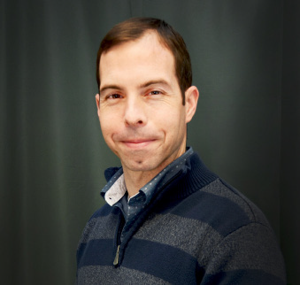 man with brown hair and grey and navy striped sweater