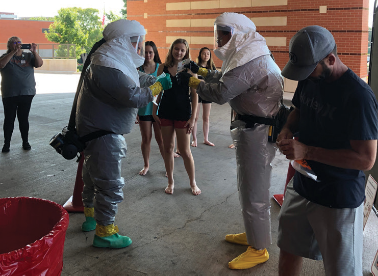 High school girls watching men in hazmat suits demonstration