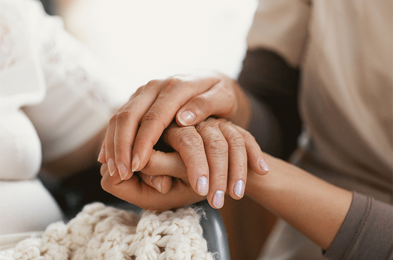 Young lady holding hands of senior woman in hospital